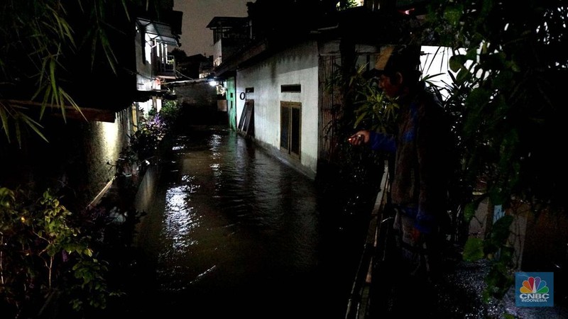 Sejumlah warga melintas di tengah banjir di RW 06 Jatipadang, Jakarta Selatan, (6/7/2025). (CNBC Indonesia/Muhammad Sabki)