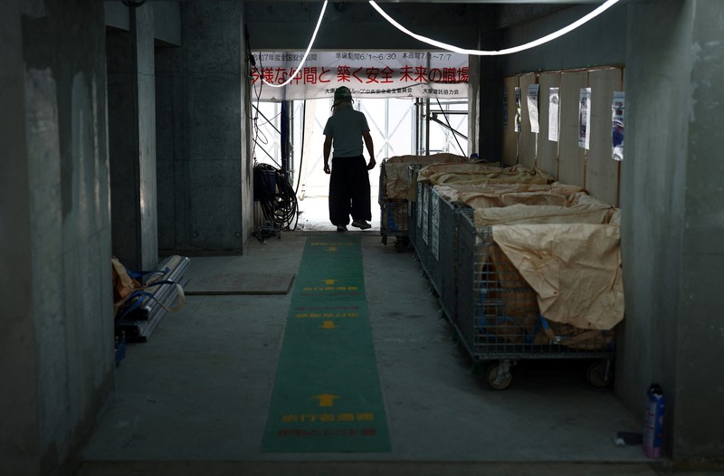 ASIA-WEATHER/JAPAN-HEATWAVE Heat-exposed workers, wearing air-conditioned jackets, which have cooling fans on their backs, are seen at the top of an apartment building under construction, as the Japanese government issued a heatstroke alert in Tokyo and other prefectures, in Tokyo, Japan, July 7, 2025. REUTERS/Issei Kato