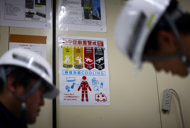 ASIA-WEATHER/JAPAN-HEATWAVE Heat-exposed workers, wearing air-conditioned jackets, which have cooling fans on their backs, are seen at the top of an apartment building under construction, as the Japanese government issued a heatstroke alert in Tokyo and other prefectures, in Tokyo, Japan, July 7, 2025. REUTERS/Issei Kato