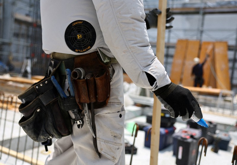 Heat-exposed workers, wearing air-conditioned jackets, which have cooling fans on their backs, are seen at the top of an apartment building under construction, as the Japanese government issued a heatstroke alert in Tokyo and other prefectures, in Tokyo, Japan, July 7, 2025. REUTERS/Issei Kato
