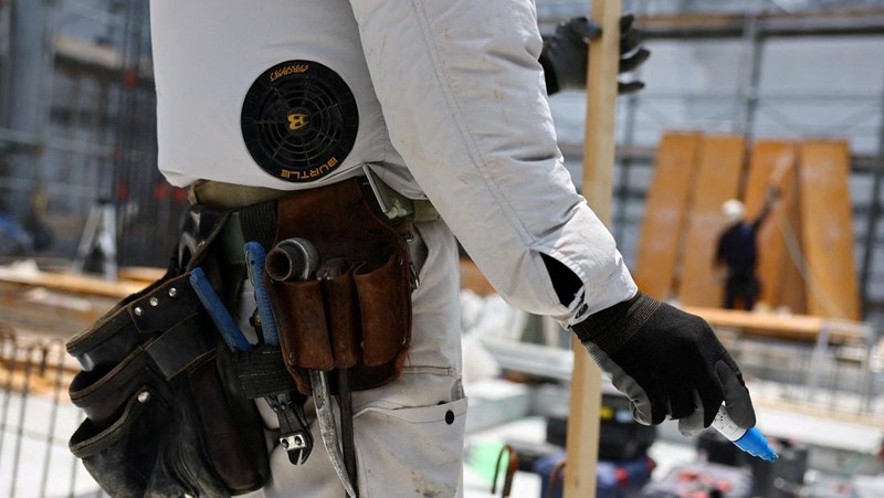 Heat-exposed workers, wearing air-conditioned jackets, which have cooling fans on their backs, are seen at the top of an apartment building under construction, as the Japanese government issued a heatstroke alert in Tokyo and other prefectures, in Tokyo, Japan, July 7, 2025. REUTERS/Issei Kato
