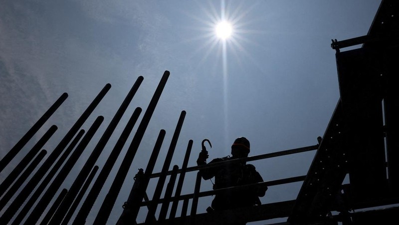Heat-exposed workers, wearing air-conditioned jackets, which have cooling fans on their backs, are seen at the top of an apartment building under construction, as the Japanese government issued a heatstroke alert in Tokyo and other prefectures, in Tokyo, Japan, July 7, 2025. REUTERS/Issei Kato
