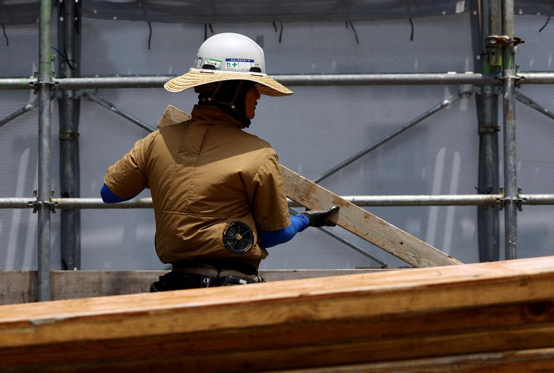 ASIA-WEATHER/JAPAN-HEATWAVE Heat-exposed workers, wearing air-conditioned jackets, which have cooling fans on their backs, are seen at the top of an apartment building under construction, as the Japanese government issued a heatstroke alert in Tokyo and other prefectures, in Tokyo, Japan, July 7, 2025. REUTERS/Issei Kato