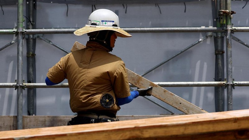 Heat-exposed workers, wearing air-conditioned jackets, which have cooling fans on their backs, are seen at the top of an apartment building under construction, as the Japanese government issued a heatstroke alert in Tokyo and other prefectures, in Tokyo, Japan, July 7, 2025. REUTERS/Issei Kato