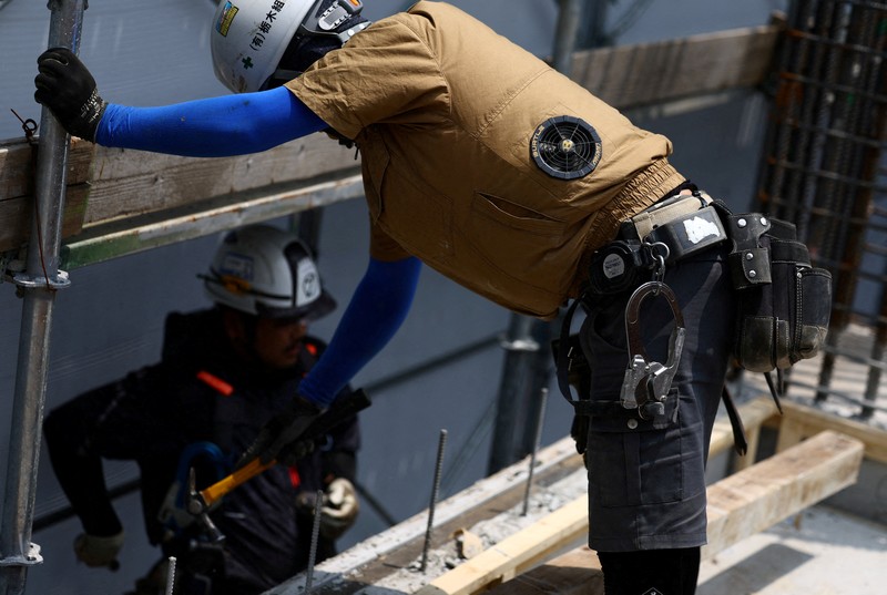 ASIA-WEATHER/JAPAN-HEATWAVE Heat-exposed workers, wearing air-conditioned jackets, which have cooling fans on their backs, are seen at the top of an apartment building under construction, as the Japanese government issued a heatstroke alert in Tokyo and other prefectures, in Tokyo, Japan, July 7, 2025. REUTERS/Issei Kato