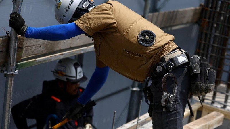 Heat-exposed workers, wearing air-conditioned jackets, which have cooling fans on their backs, are seen at the top of an apartment building under construction, as the Japanese government issued a heatstroke alert in Tokyo and other prefectures, in Tokyo, Japan, July 7, 2025. REUTERS/Issei Kato