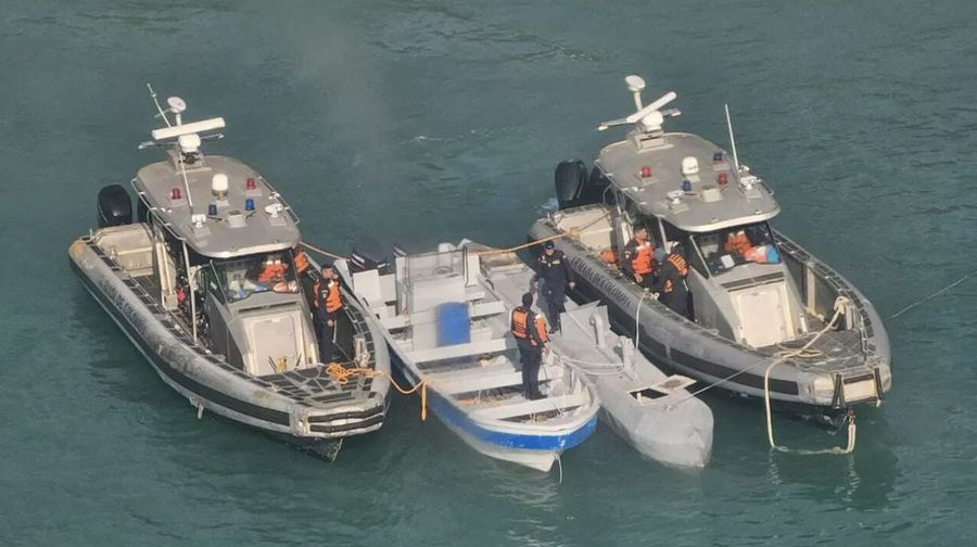 Foto yang dirilis oleh kantor pers Angkatan Laut Kolombia menunjukkan sebuah kapal selam semi-nir awak, yang dikenal sebagai Kapal Profil Rendah, di antara dua kapal Angkatan Laut Kolombia, 2 Juli 2025. (Handout/Angkatan Laut Kolombia/AFP)