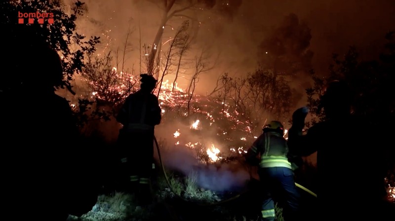 Anak-anak menyaksikan helikopter terbang untuk membantu memadamkan kebakaran hutan yang terjadi di Xerta, salah satu desa terkurung di provinsi Tarragona di Catalonia, Spanyol, 8 Juli 2025. (REUTERS/Nacho Doce)
