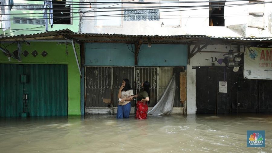 Sejumlah pengendara motor menggunakan jasa pikulan gerobak untuk melintasi genangan air nan membanjiri jalan Hasyim Ashari di Ciledug Indah, Tangerang, Banten, Selasa (8/7/2025). (librosfullgratis.com/Tri Susilo)