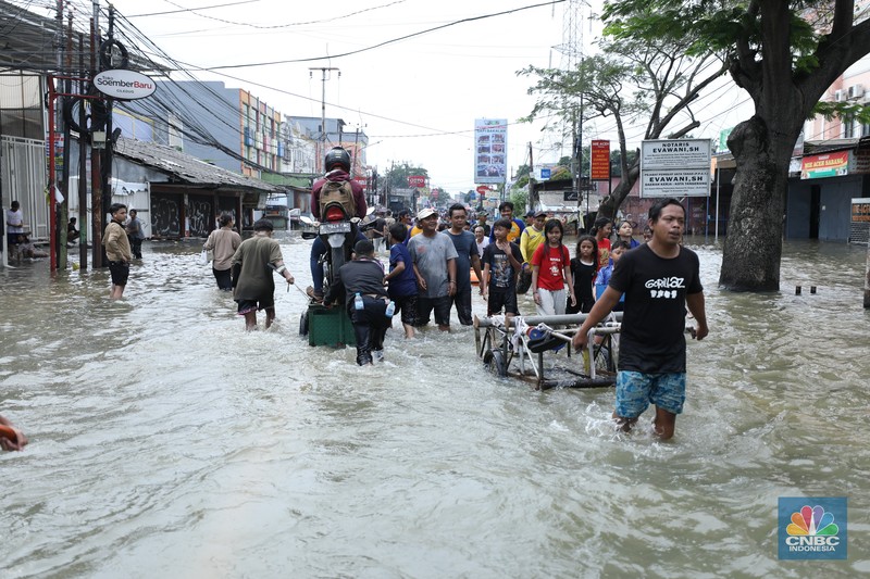 Sejumlah pengendara motor menggunakan jasa angkutan gerobak untuk melintasi genangan air yang membanjiri jalan Hasyim Ashari di Ciledug Indah, Tangerang, Banten, Selasa (8/7/2025). Sejumlah pengendara motor menggunakan jasa angkutan gerobak untuk melintasi genangan air yang membanjiri jalan Hasyim Ashari di Ciledug Indah, Tangerang, Banten, Selasa (8/7/2025). (CNBC Indonesia/Tri Susilo)