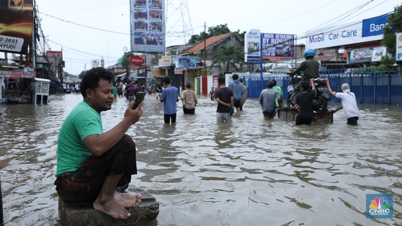 Sejumlah pengendara motor menggunakan jasa angkutan gerobak untuk melintasi genangan air yang membanjiri jalan Hasyim Ashari di Ciledug Indah, Tangerang, Banten, Selasa (8/7/2025). Sejumlah pengendara motor menggunakan jasa angkutan gerobak untuk melintasi genangan air yang membanjiri jalan Hasyim Ashari di Ciledug Indah, Tangerang, Banten, Selasa (8/7/2025). (CNBC Indonesia/Tri Susilo)