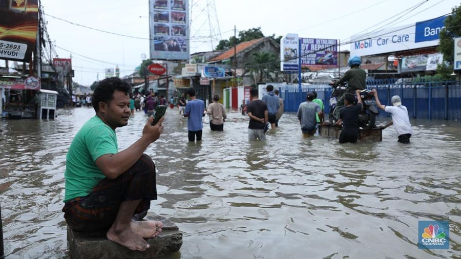 Sejumlah pengendara motor menggunakan jasa pikulan gerobak untuk melintasi genangan air nan membanjiri jalan Hasyim Ashari di Ciledug Indah, Tangerang, Banten, Selasa (8/7/2025). (librosfullgratis.com/Tri Susilo)