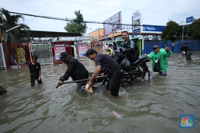 Sejumlah pengendara motor menggunakan jasa angkutan gerobak untuk melintasi genangan air yang membanjiri jalan Hasyim Ashari di Ciledug Indah, Tangerang, Banten, Selasa (8/7/2025). Sejumlah pengendara motor menggunakan jasa angkutan gerobak untuk melintasi genangan air yang membanjiri jalan Hasyim Ashari di Ciledug Indah, Tangerang, Banten, Selasa (8/7/2025). (CNBC Indonesia/Tri Susilo)