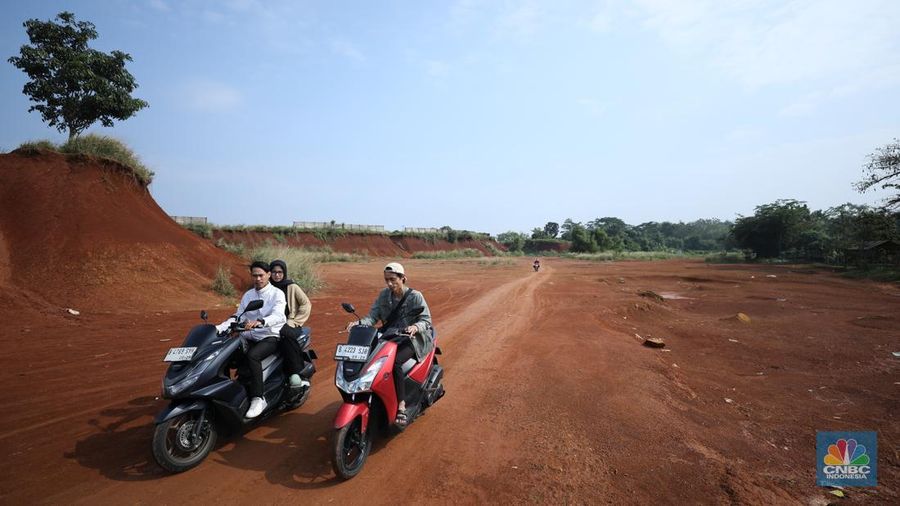 Warga melintasi Tanah Merah dengan sepeda motor di kawasan Cipayung, Depok, Jawa Barat, Rabu (9/7/2025). (CNBC Indonesia/Tri Susilo)