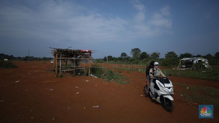 Warga melintasi Tanah Merah dengan sepeda motor di kawasan Cipayung, Depok, Jawa Barat, Rabu (9/7/2025). (CNBC Indonesia/Tri Susilo)