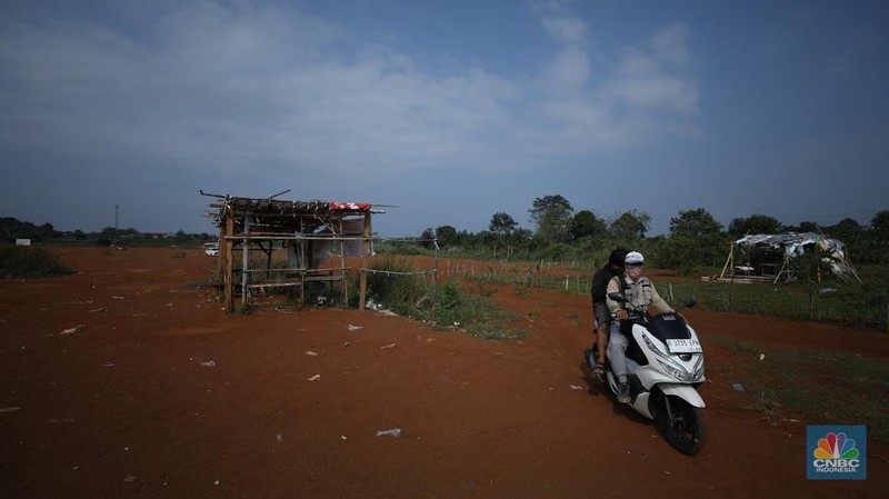 Warga melintasi Tanah Merah dengan sepeda motor di kawasan Cipayung, Depok, Jawa Barat, Rabu (9/7/2025). (CNBC Indonesia/Tri Susilo)