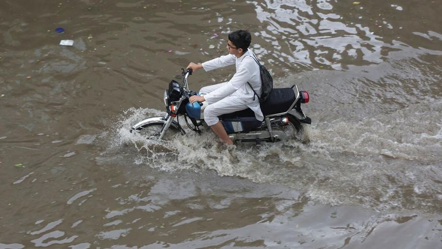 Seseorang mengendarai sepeda motor melewati jalan yang banjir setelah hujan deras di Lahore, Pakistan, 9 Juli 2025. (REUTERS/Mohsin Raza)