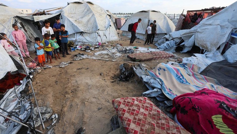 Palestinian children inspect the damage at the site of an overnight Israeli airstrike that hit a tent sheltering displaced people, in Khan Younis, southern Gaza Strip, July 12, 2025. REUTERS/Ramadan Abed
