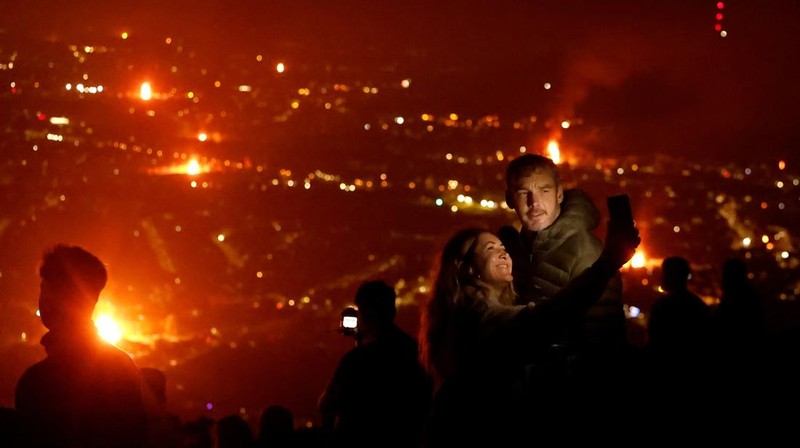 A loyalist bonfire burns after being set alight, featuring a model effigy of a boat containing mannequins portrayed as migrants in lifejackets, with a sign reading 