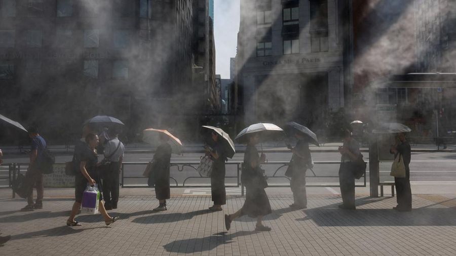 People exposed to the sun hold parasols as they wait for a bus near a cooling mist as the Japanese government issued a heatstroke alert in Tokyo and other prefectures, in Tokyo, Japan July 9, 2025. REUTERS/Issei Kato TPX IMAGES OF THE DAY