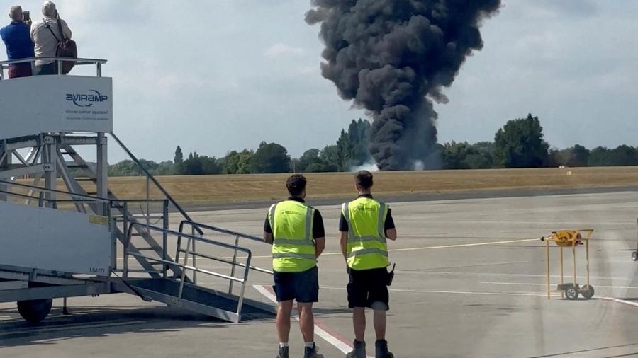 Gumpalan asap hitam mengepul dari area dekat landasan pacu setelah sebuah pesawat kecil jatuh, seperti yang terlihat dari dalam sebuah gedung di Bandara London Southend, di Southend, Inggris, 13 Juli 2025, dalam tangkapan layar yang diperoleh dari video media sosial. (@agussromagnoli via X/via REUTERS)