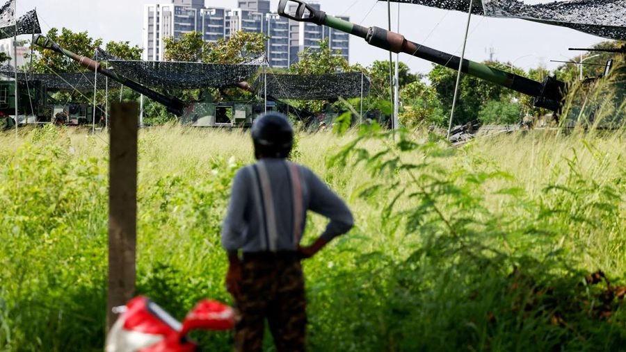 Seorang pria menunggu untuk menyeberang jalan saat kendaraan lapis baja CM-34 Clouded Leopard ikut serta dalam latihan simulasi serangan China, di daerah perkotaan sebagai bagian dari latihan tahunan Han Kuang, di Kota Taipei Baru, Taiwan, 15 Juli 2025. (REUTERS/Annabelle Chih)
