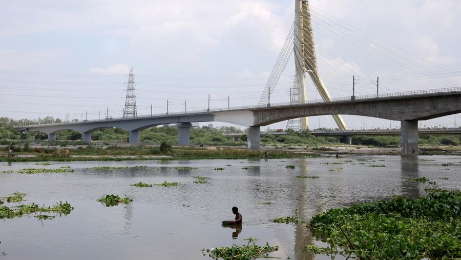 A man searches for coins and other valuable items thrown by Hindu devotees as religious offerings in the waters of river Yamuna in New Delhi, India, June 27, 2025. REUTERS/Bhawika Chhabra