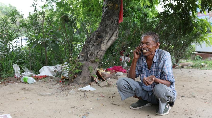 Ramu Gupta, a 67-year-old man who goes to the Yamuna River to hunt for coins and other valuables, reacts as he speaks with a friend on his mobile phone after finishing his hunt for the day, in New Delhi, India, June 27, 2025. REUTERS/Bhawika Chhabra