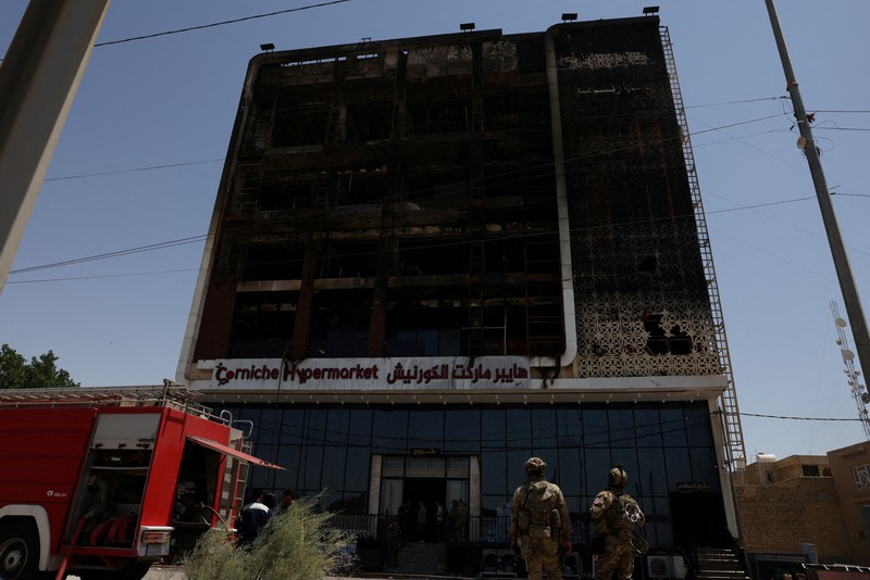 Truk pemadam kebakaran berdiri di samping reruntuhan pusat perbelanjaan, setelah kebakaran besar semalam yang menewaskan puluhan orang, di al-Kut, provinsi Wasit, Irak, 17 Juli 2025. (REUTERS/Ahmed Saad)