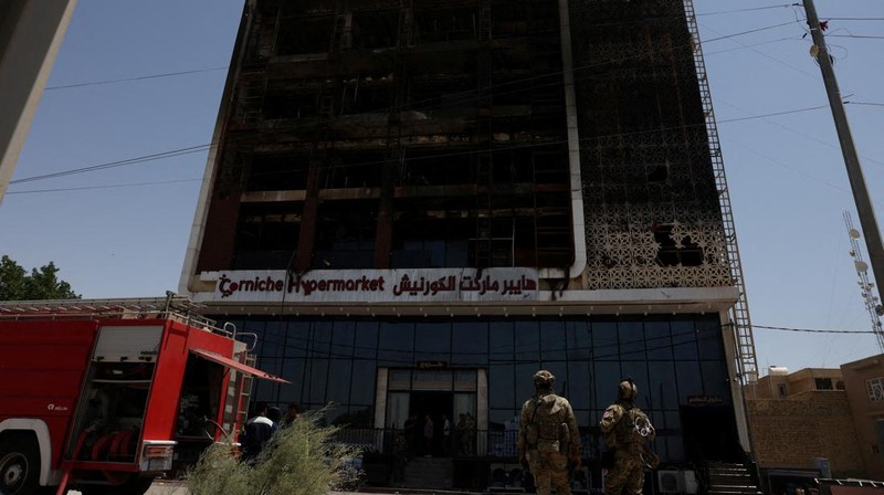 Truk pemadam kebakaran berdiri di samping reruntuhan pusat perbelanjaan, setelah kebakaran besar semalam yang menewaskan puluhan orang, di al-Kut, provinsi Wasit, Irak, 17 Juli 2025. (REUTERS/Ahmed Saad)