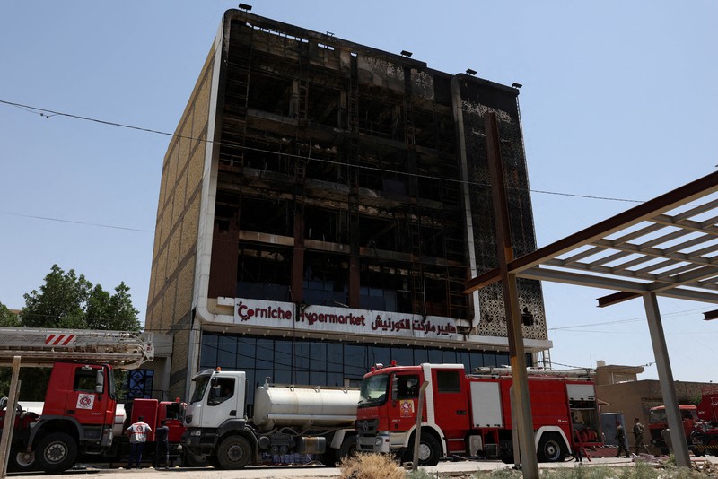 Truk pemadam kebakaran berdiri di samping reruntuhan pusat perbelanjaan, setelah kebakaran besar semalam yang menewaskan puluhan orang, di al-Kut, provinsi Wasit, Irak, 17 Juli 2025. (REUTERS/Ahmed Saad)