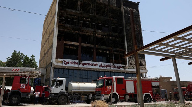 Truk pemadam kebakaran berdiri di samping reruntuhan pusat perbelanjaan, setelah kebakaran besar semalam yang menewaskan puluhan orang, di al-Kut, provinsi Wasit, Irak, 17 Juli 2025. (REUTERS/Ahmed Saad)