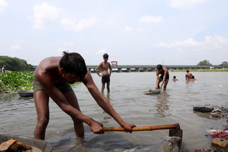 Ramu Gupta, seorang pria berusia 67 tahun yang pergi ke sungai untuk berburu koin dan barang berharga lainnya, mengeluarkan tas berisi plastik dari perairan sungai Yamuna di New Delhi, India, 26 Juni 2025. (REUTERS/Bhawika Chhabra)