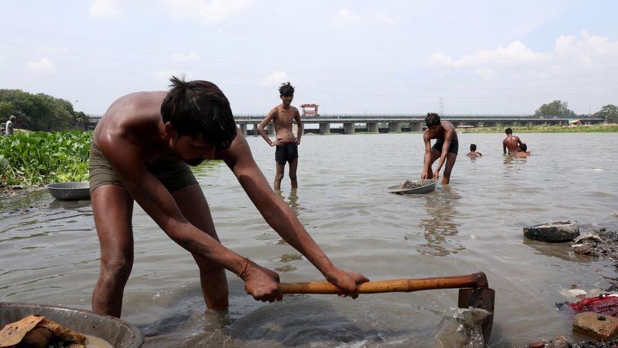 Ramu Gupta, seorang pria berusia 67 tahun yang pergi ke sungai untuk berburu koin dan barang berharga lainnya, mengeluarkan tas berisi plastik dari perairan sungai Yamuna di New Delhi, India, 26 Juni 2025. Ramu Gupta, seorang pria berusia 67 tahun yang pergi ke sungai untuk berburu koin dan barang berharga lainnya, mengeluarkan tas berisi plastik dari perairan sungai Yamuna di New Delhi, India, 26 Juni 2025. (REUTERS/Bhawika Chhabra)