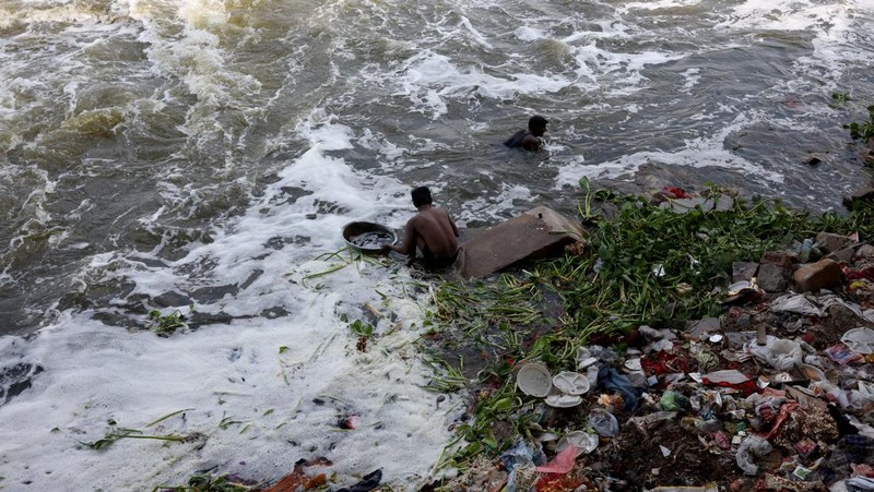 Ramu Gupta, seorang pria berusia 67 tahun yang pergi ke sungai untuk berburu koin dan barang berharga lainnya, mengeluarkan tas berisi plastik dari perairan sungai Yamuna di New Delhi, India, 26 Juni 2025. (REUTERS/Bhawika Chhabra)