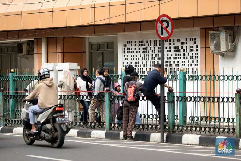 penumpang krl, commuterline, kai, Sejumlah warga calon penumpang commuterline melompati pagar pembatas antara jalan dan Stasiun Cikini di Jakarta, Jumat (18/7/2025). (CNBC Indonesia/Tri Susilo)