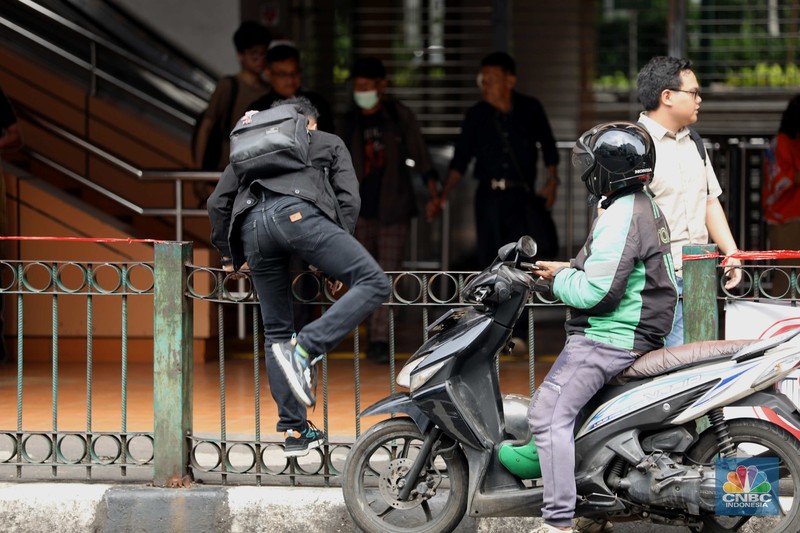 penumpang krl, commuterline, kai, Sejumlah warga calon penumpang commuterline melompati pagar pembatas antara jalan dan Stasiun Cikini di Jakarta, Jumat (18/7/2025). (CNBC Indonesia/Tri Susilo)