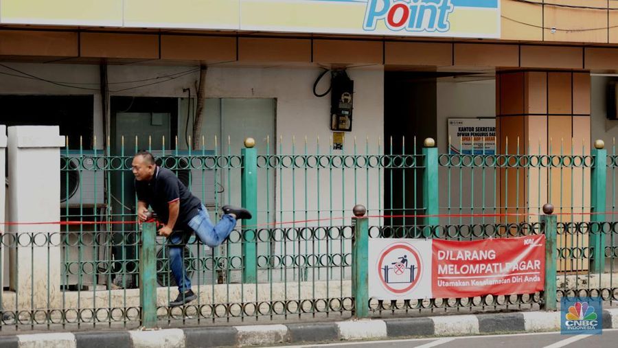 Sejumlah warga calon penumpang commuterline melompati pagar pembatas antara jalan dan Stasiun Cikini di Jakarta, Jumat (18/7/2025). (CNBC Indonesia/Tri Susilo)