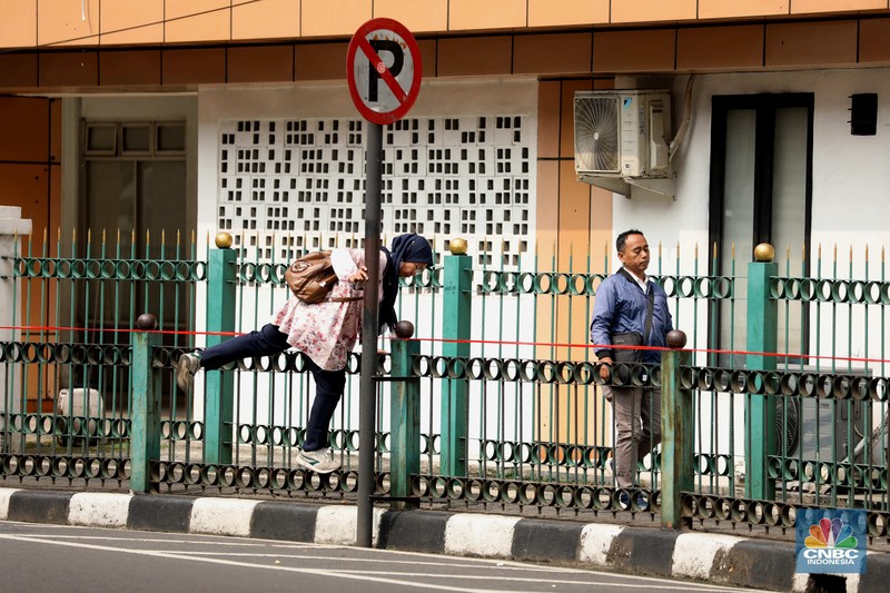 penumpang krl, commuterline, kai, Sejumlah warga calon penumpang commuterline melompati pagar pembatas antara jalan dan Stasiun Cikini di Jakarta, Jumat (18/7/2025). (CNBC Indonesia/Tri Susilo)