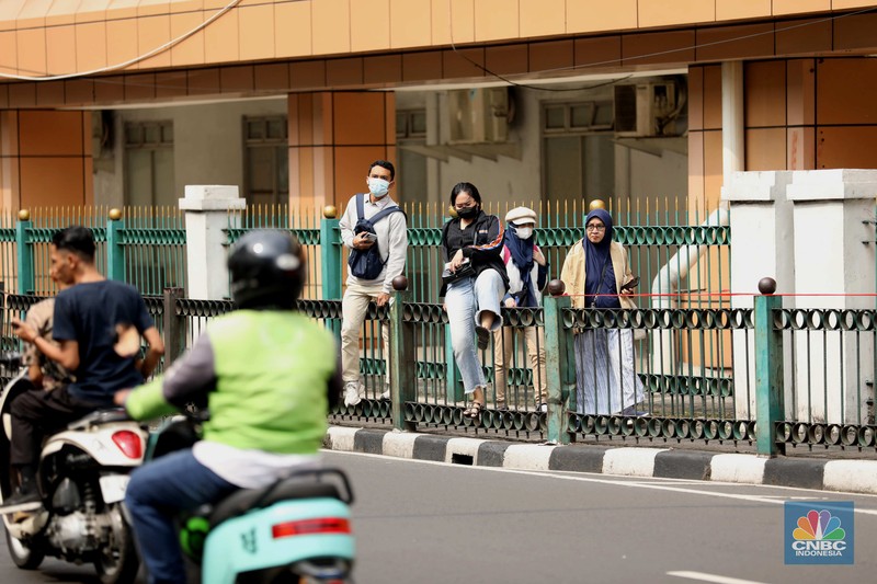 penumpang krl, commuterline, kai, Sejumlah warga calon penumpang commuterline melompati pagar pembatas antara jalan dan Stasiun Cikini di Jakarta, Jumat (18/7/2025). (CNBC Indonesia/Tri Susilo)
