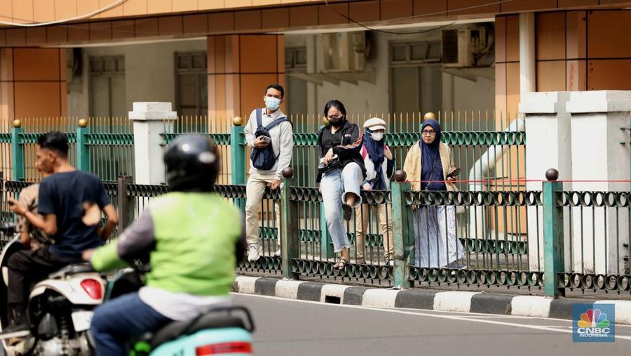 Sejumlah warga calon penumpang commuterline melompati pagar pembatas antara jalan dan Stasiun Cikini di Jakarta, Jumat (18/7/2025). (CNBC Indonesia/Tri Susilo)