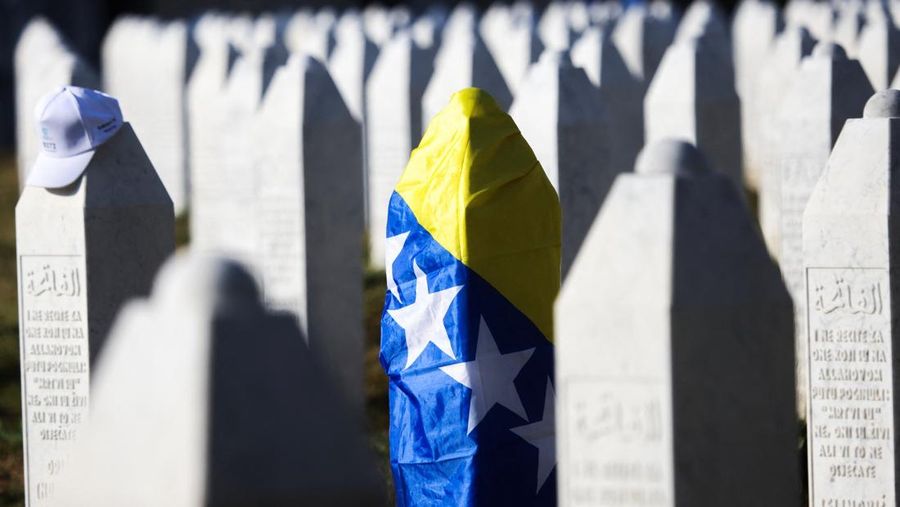 Sebuah batu nisan berbalut bendera Bosnia dan Herzegovina berdiri di antara batu nisan korban lain yang tewas dalam genosida Srebrenica, di Monumen Genosida Srebrenica di Potocari, Bosnia dan Herzegovina, 11 Juli 2025. (REUTERS/Amel Emric)