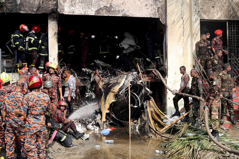 Petugas pemadam kebakaran berupaya membersihkan puing-puing bangunan setelah pesawat latih angkatan udara jatuh di kampus Milestone College, di Dhaka, Bangladesh, 21 Juli 2025. (REUTERS/Stringer)