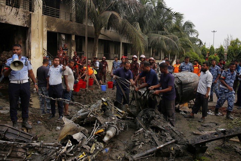 Petugas pemadam kebakaran berupaya membersihkan puing-puing bangunan setelah pesawat latih angkatan udara jatuh di kampus Milestone College, di Dhaka, Bangladesh, 21 Juli 2025. (REUTERS/Stringer)