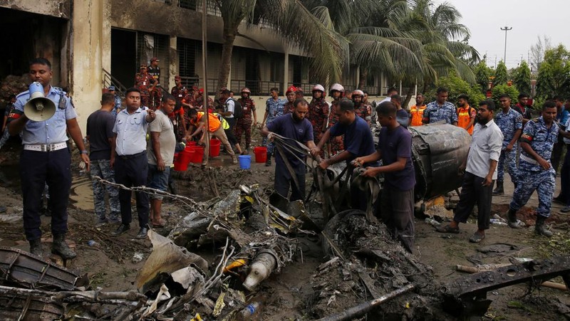 Petugas pemadam kebakaran berupaya membersihkan puing-puing bangunan setelah pesawat latih angkatan udara jatuh di kampus Milestone College, di Dhaka, Bangladesh, 21 Juli 2025. (REUTERS/Stringer)