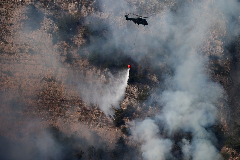 Seseorang berdiri di tengah asap saat kebakaran hutan melanda sebuah desa di Dubrava, Kosovo, 22 Juli 2025. (REUTERS/Valdrin Xhemaj)