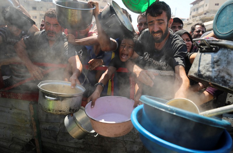ISRAEL-PALESTINIANS/GAZA-HUNGER Palestinians wait to receive food from a charity kitchen, amid a hunger crisis, in Gaza City, July 23, 2025. REUTERS/Mahmoud Issa