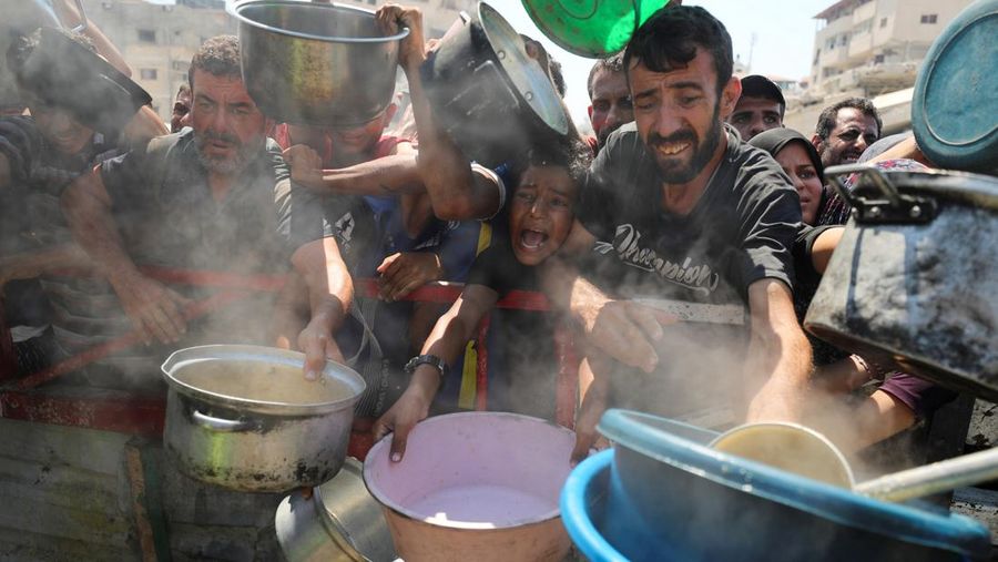 Palestinians wait to receive food from a charity kitchen, amid a hunger crisis, in Gaza City, July 23, 2025. REUTERS/Mahmoud Issa