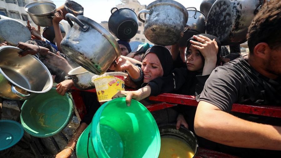 Palestinians wait to receive food from a charity kitchen, amid a hunger crisis, in Gaza City, July 23, 2025. REUTERS/Mahmoud Issa