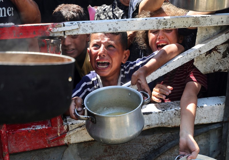 Palestinians wait to receive food from a charity kitchen, amid a hunger crisis, in Gaza City, July 23, 2025. REUTERS/Mahmoud Issa
